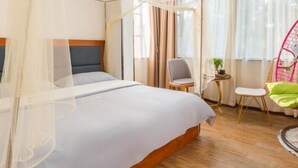 Hotellihuone, jossa on sänky, tuoli, pieni pöytä ja ikkuna, jossa on verhot.