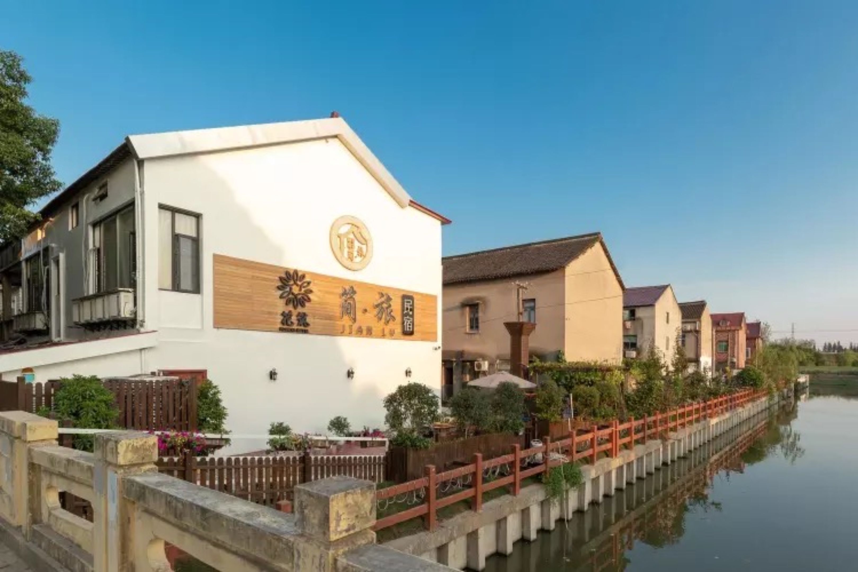 Un edificio de estilo tradicional con un letrero de madera, un canal de agua y un puente de madera.