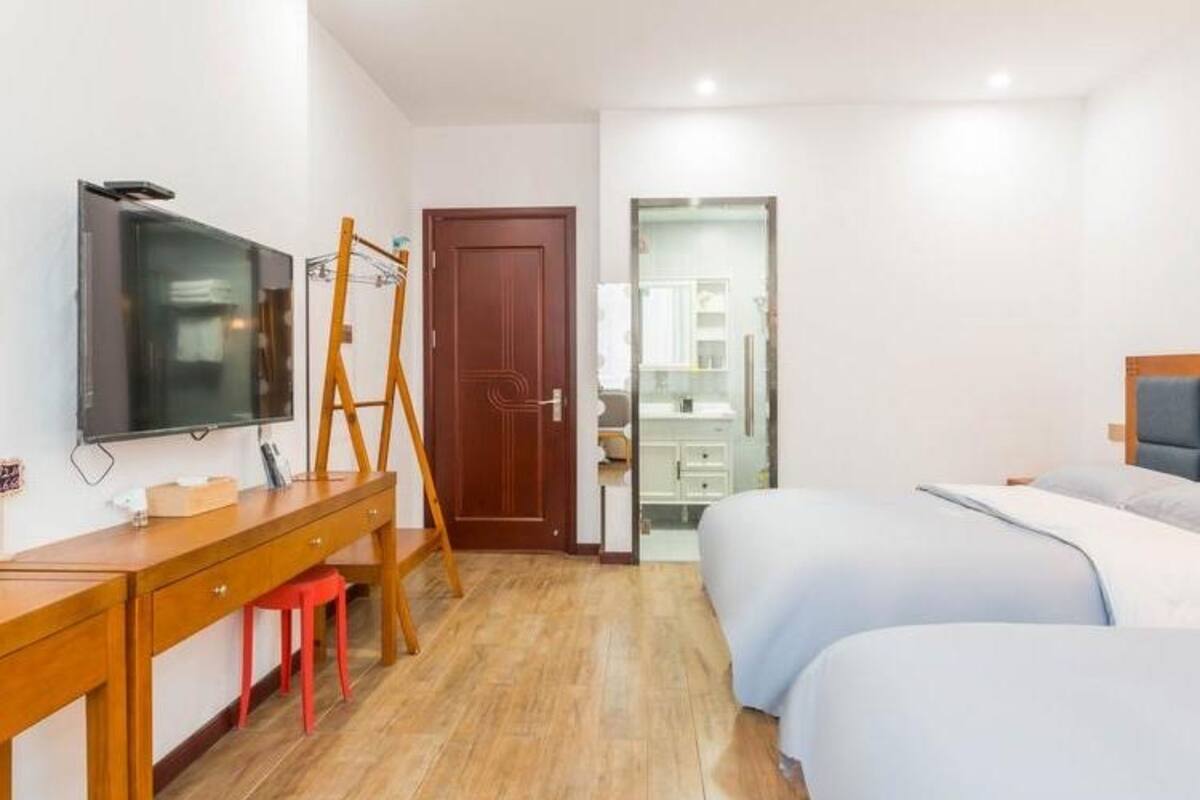 Une chambre d’hôtel avec un bureau en bois, une télévision, un lit et un miroir.