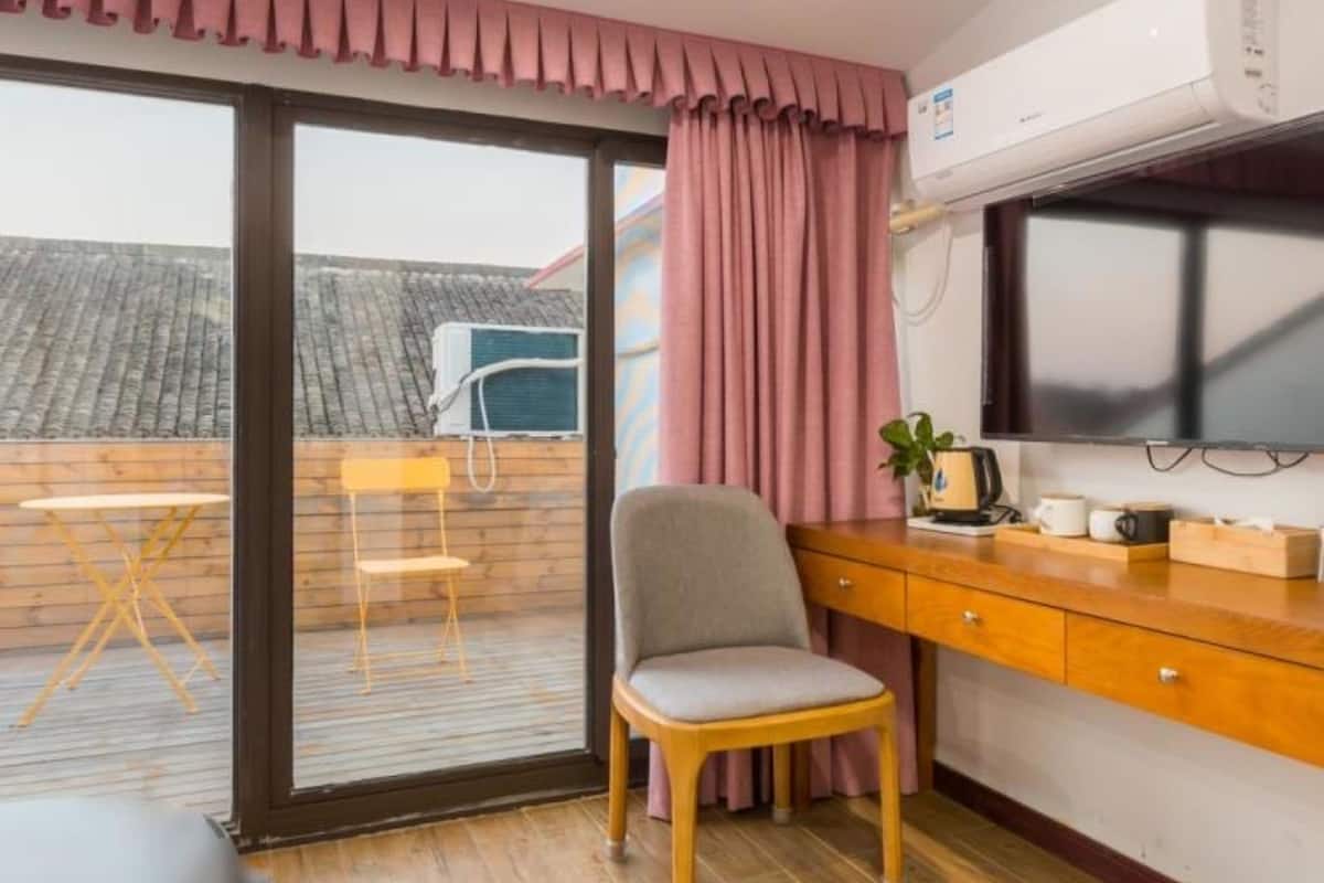Une chambre compacte dotée d’une porte-fenêtre coulissante donnant sur un balcon, d’un petit bureau avec une chaise et d’un lit.