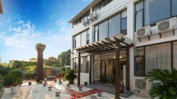A modern building with a covered patio area, large windows, and air conditioning units.