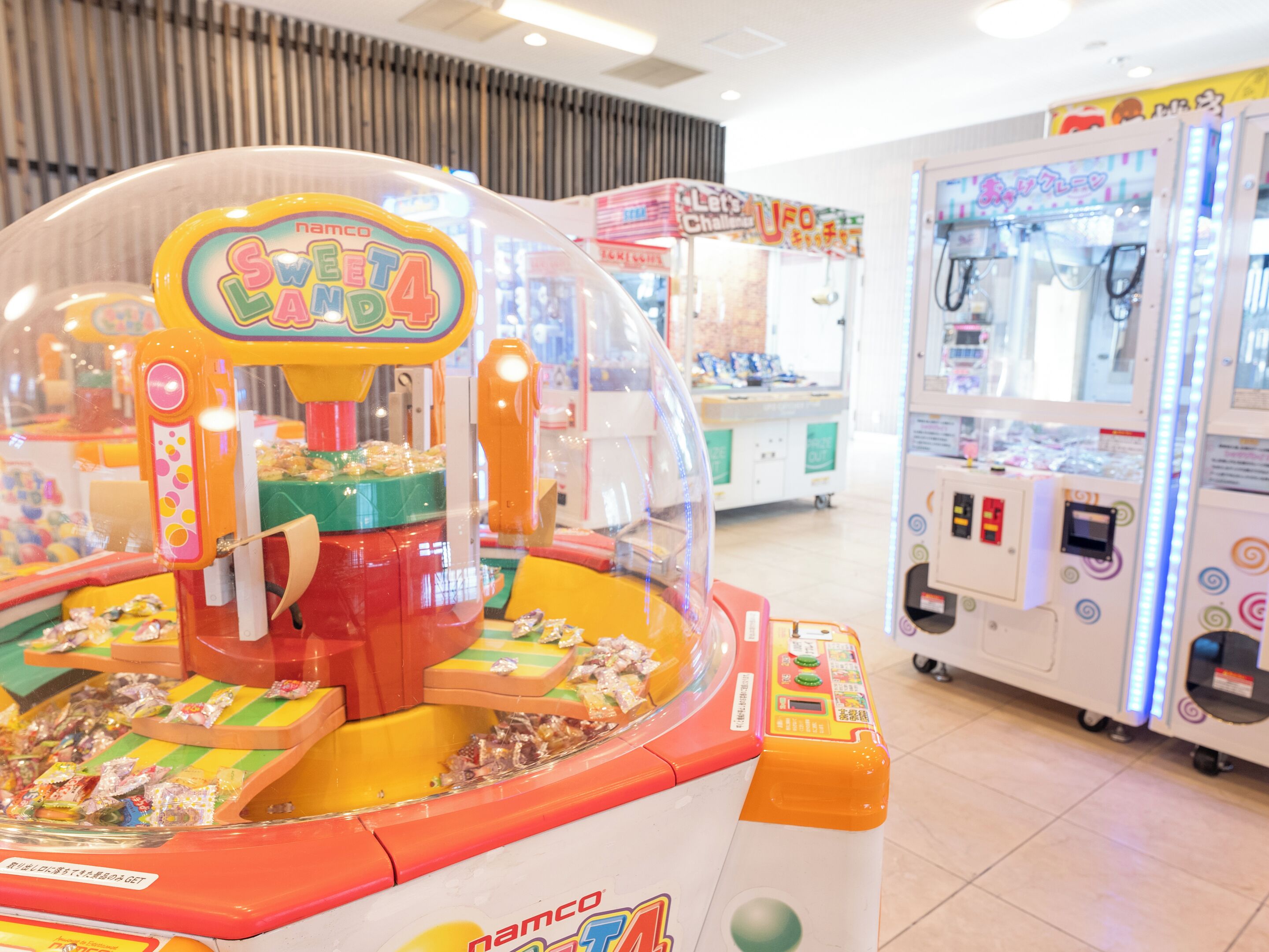 Una hilera de juegos de arcade, incluyendo una máquina de pinzas y un juego UFO Challenger.