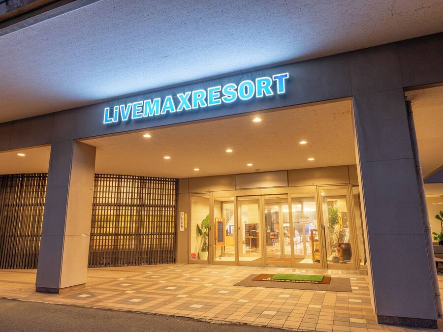 Der Eingang des Livemaxresort mit gefliestem Vorplatz, einer Glastür und einem Schild darüber.