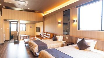A hotel room with two beds, a wooden floor, a ceiling fan, and a large window.