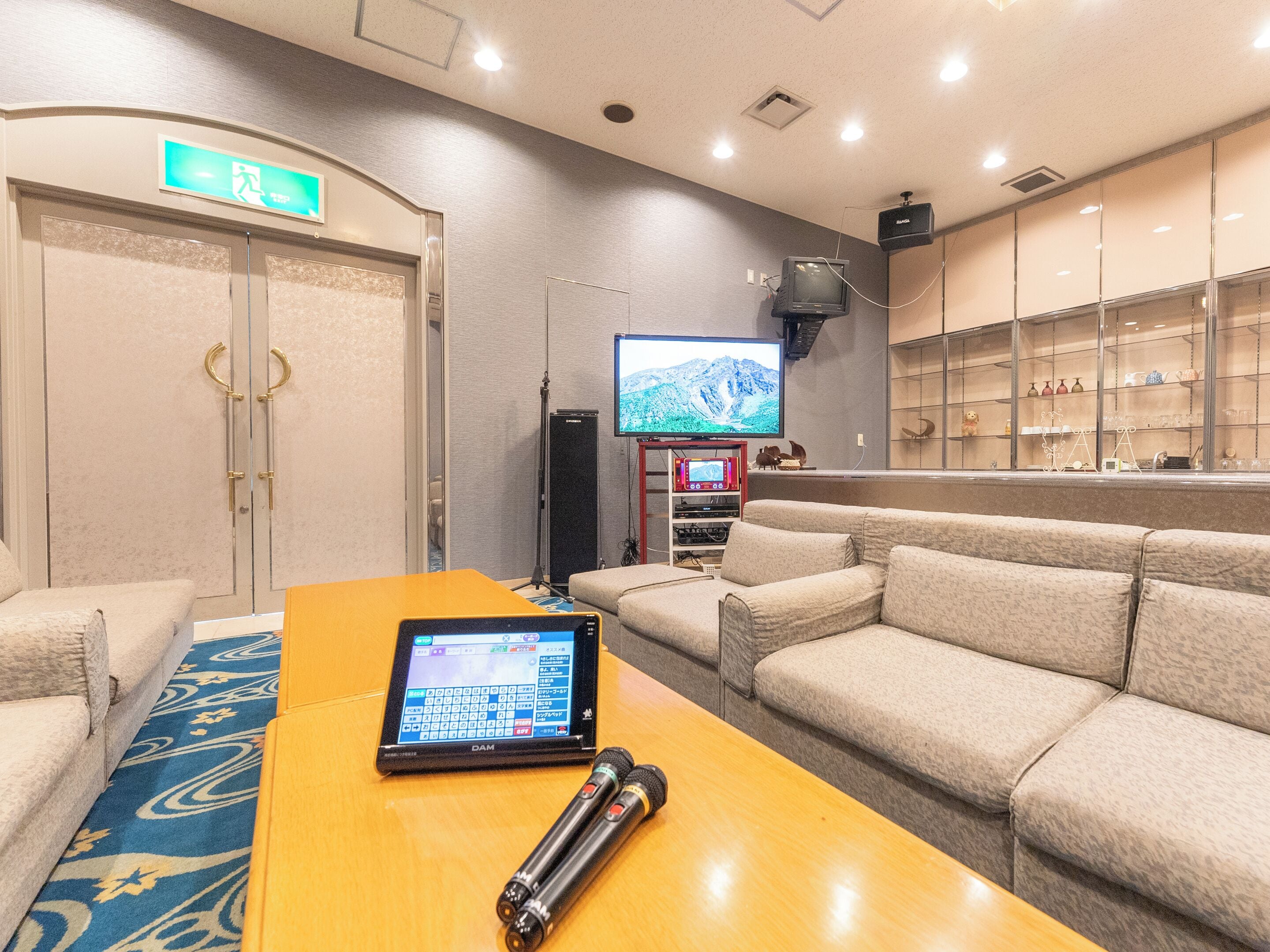 A hotel lobby with a reception desk, seating area, and a television screen.