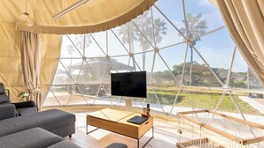 A modern tented room with a large window, a flat-screen TV, a wooden coffee table, and a pet cage. - LiVEMAX RESORT Sakurajima-seafront (Tarumizu)