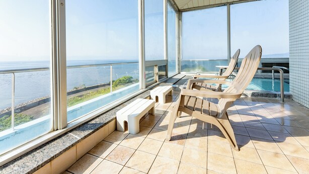 A balcony with a pool, two lounge chairs, and a small table. - LiVEMAX RESORT Sakurajima-seafront (Tarumizu)