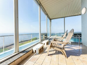 A balcony with a pool, two lounge chairs, and a small table. - LiVEMAX RESORT Sakurajima-seafront (Tarumizu)