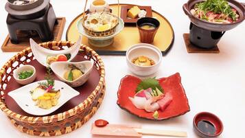 Ett urval av japanska rätter presenterade på ett träbord, inklusive sushi, sashimi och en varm gryta.