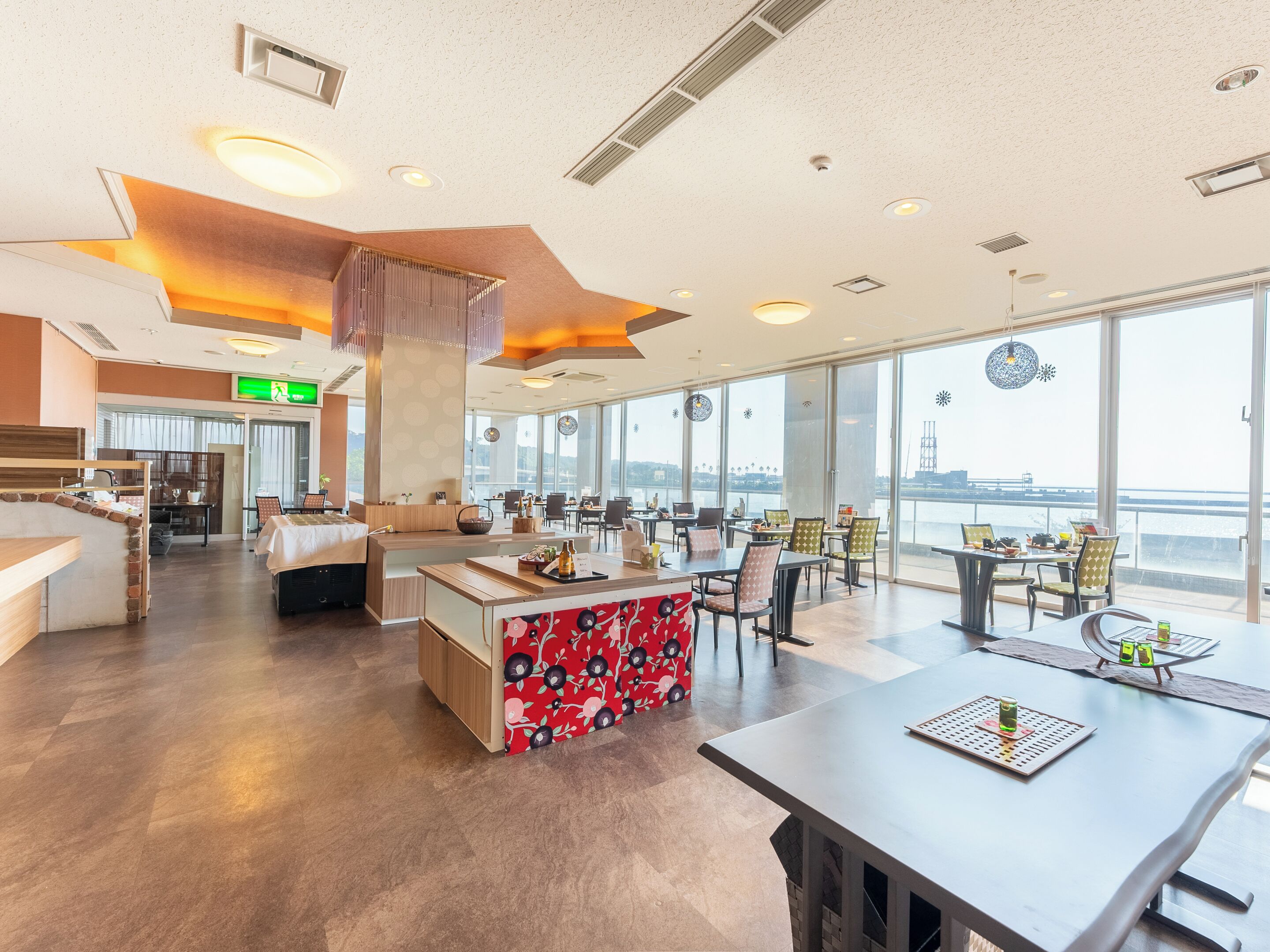 A modern restaurant with a large window view, a central bar area, and multiple seating options.
