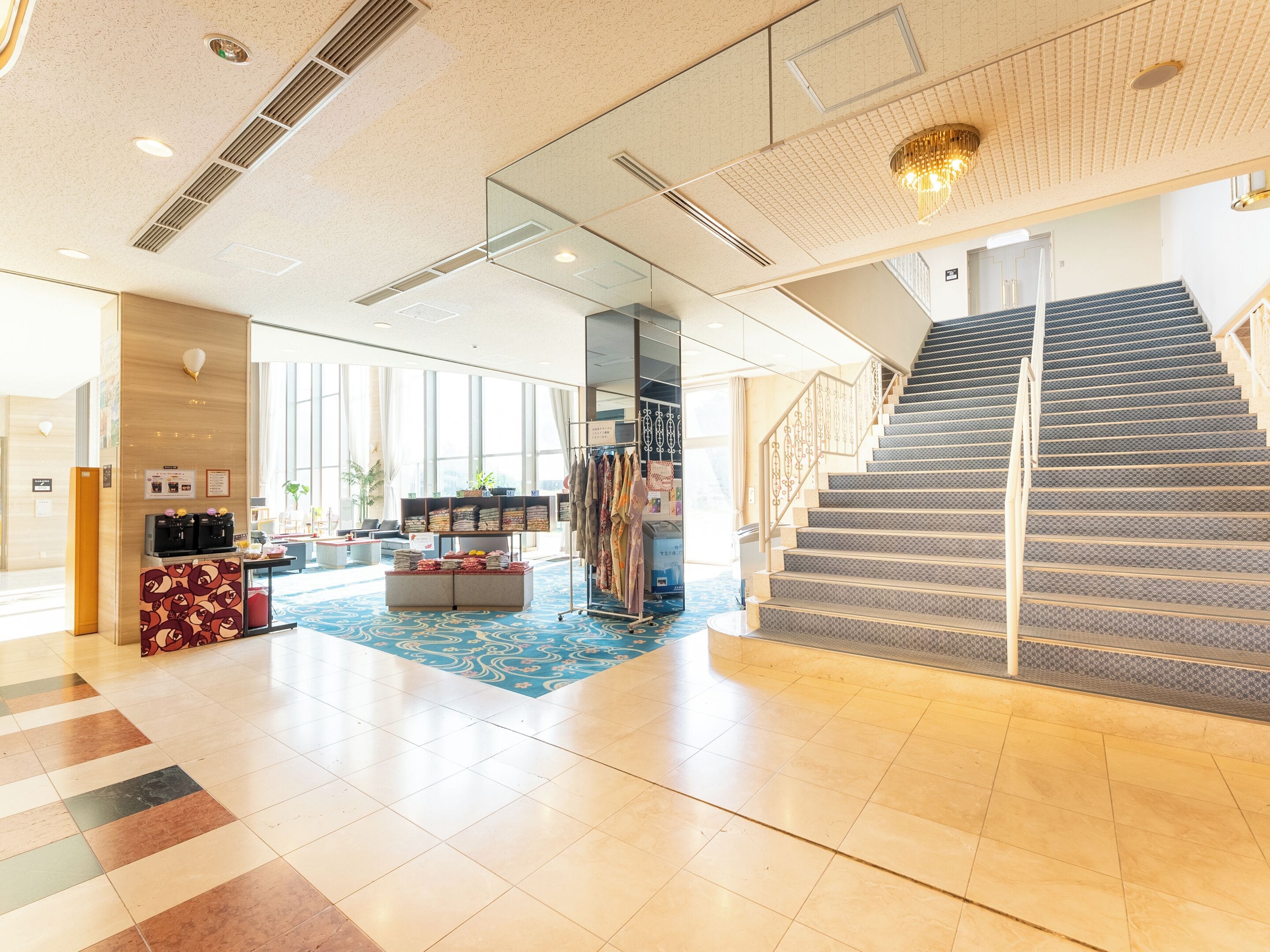 Um hall amplo com piso xadrez, escada e área de estar com tapete estampado.