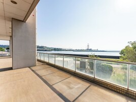 Un balcón con vistas a un río, un puente y edificios al fondo.