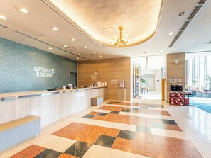 Un hall d'hôtel comprenant un comptoir d'enregistrement, un lustre et un bureau d'accueil.