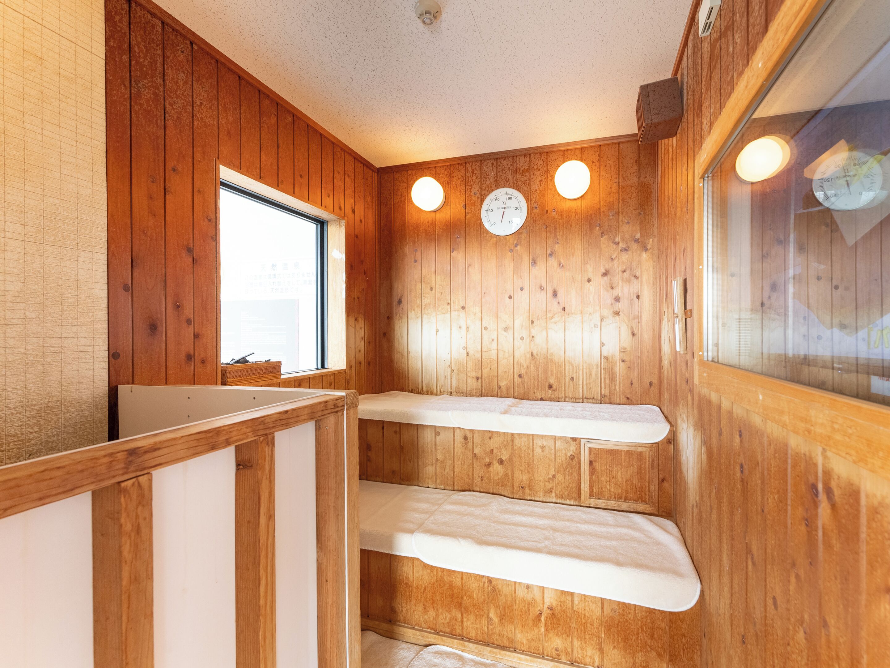 A wooden interior with a bench, a clock, and a window.