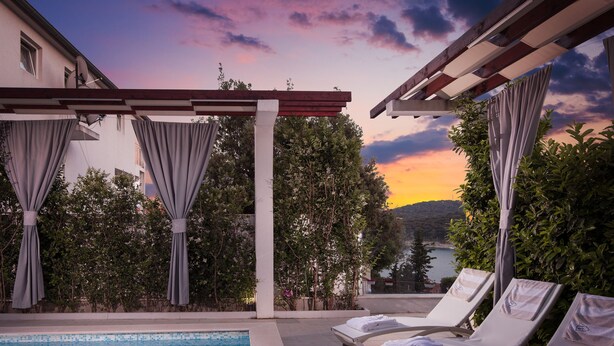 A poolside area with lounge chairs and a pergola. - Villa Martinis (Rogoznica)