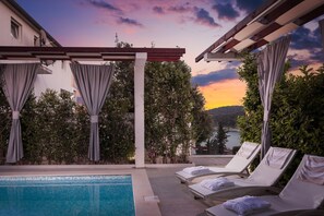 A poolside area with lounge chairs and a pergola. - Villa Martinis (Rogoznica)