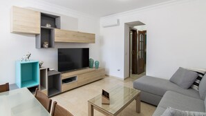 A modern living room with a flat-screen TV, a grey sofa, and a glass coffee table. - Las Brisas de Puerto Rico (Mogán)