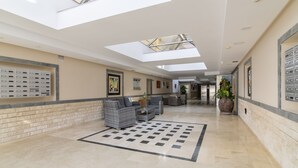 A spacious lobby with a high ceiling, skylights, and a central seating area with sofas and a coffee table. - Las Brisas de Puerto Rico (Mogán)