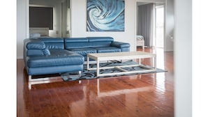 A modern living room with a blue leather sectional sofa, a white coffee table, and a blue abstract painting on the wall. - Picturesque on Passage - Whitsundays (Shute Harbour)