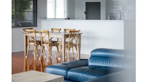 A modern kitchen with a white countertop and a dining area with wooden chairs. - Picturesque on Passage - Whitsundays (Shute Harbour)