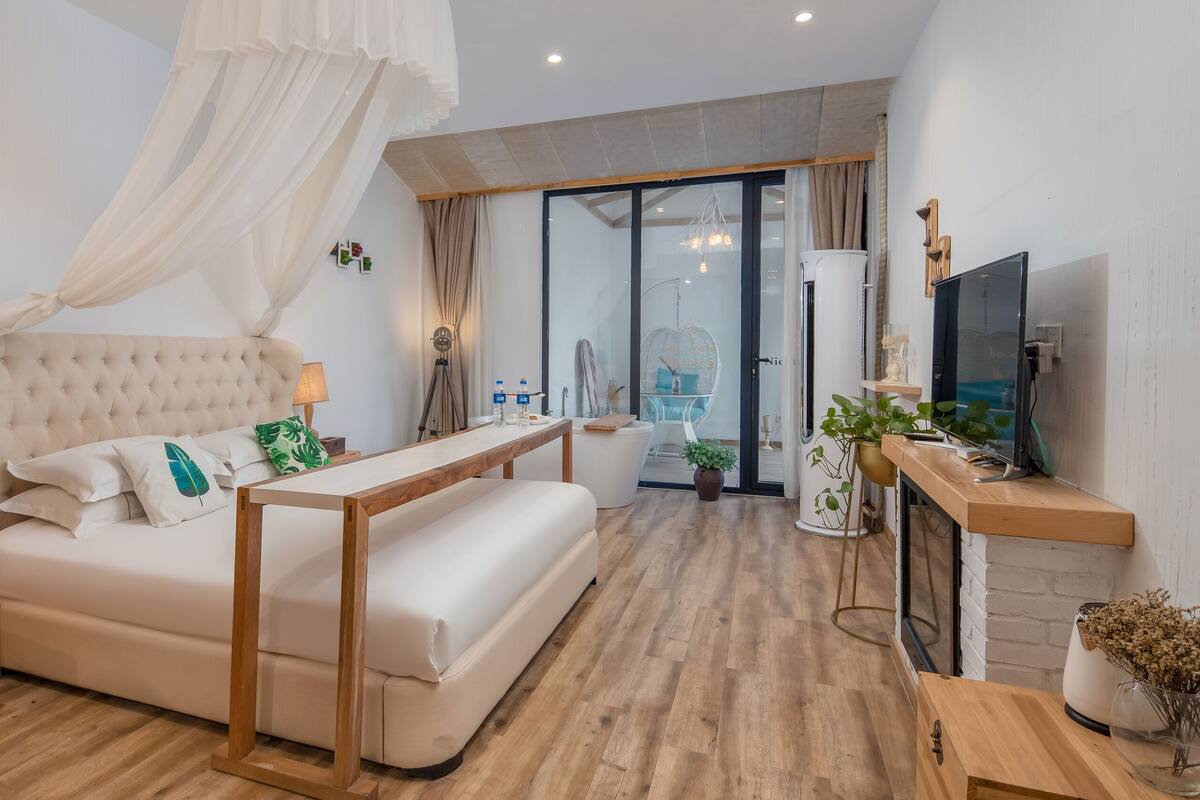 Un dormitorio con cama, mesita de noche, lámpara y un mueble para televisión con televisor.