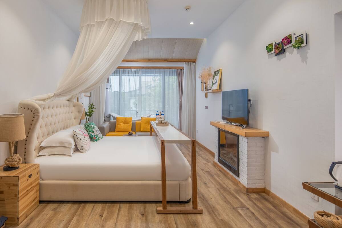 Un dormitorio con cama, mesita de noche, lámpara y televisor.