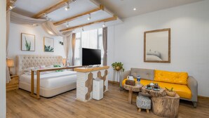 A modern living room with a sofa, a TV, a coffee table, and a plant. - Floral Hotel Yipin Visual Arts Xitang (Jiaxing)