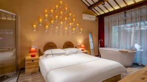 A bedroom with a large bed, two bedside tables with lamps, a wooden headboard, a wall-mounted air conditioning unit, a large window with sheer curtains, and a freestanding bathtub. - Floral Hotel Yipin Visual Arts Xitang (Jiaxing)