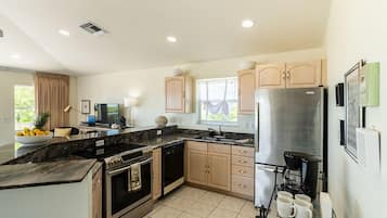 A modern kitchen with a large island, stainless steel appliances, and a coffee maker.