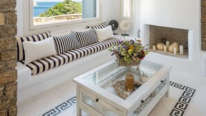 Ein modernes Wohnzimmer mit Steinwand, weißem Kamin, einem gestreiften Sofa und einem Glastisch.