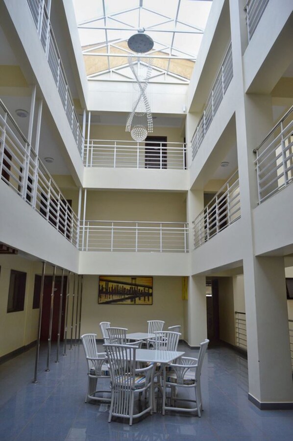 A multi-level atrium with a central open space, white railings, and a hanging chandelier. - Cranes Suites Hotel (Kitale)