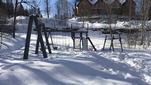 A snow-covered outdoor area with swings and a wooden structure. - Stunning 2 bed Condo in Les Manoirs, Mont-Tremblant (Mont-Tremblant)