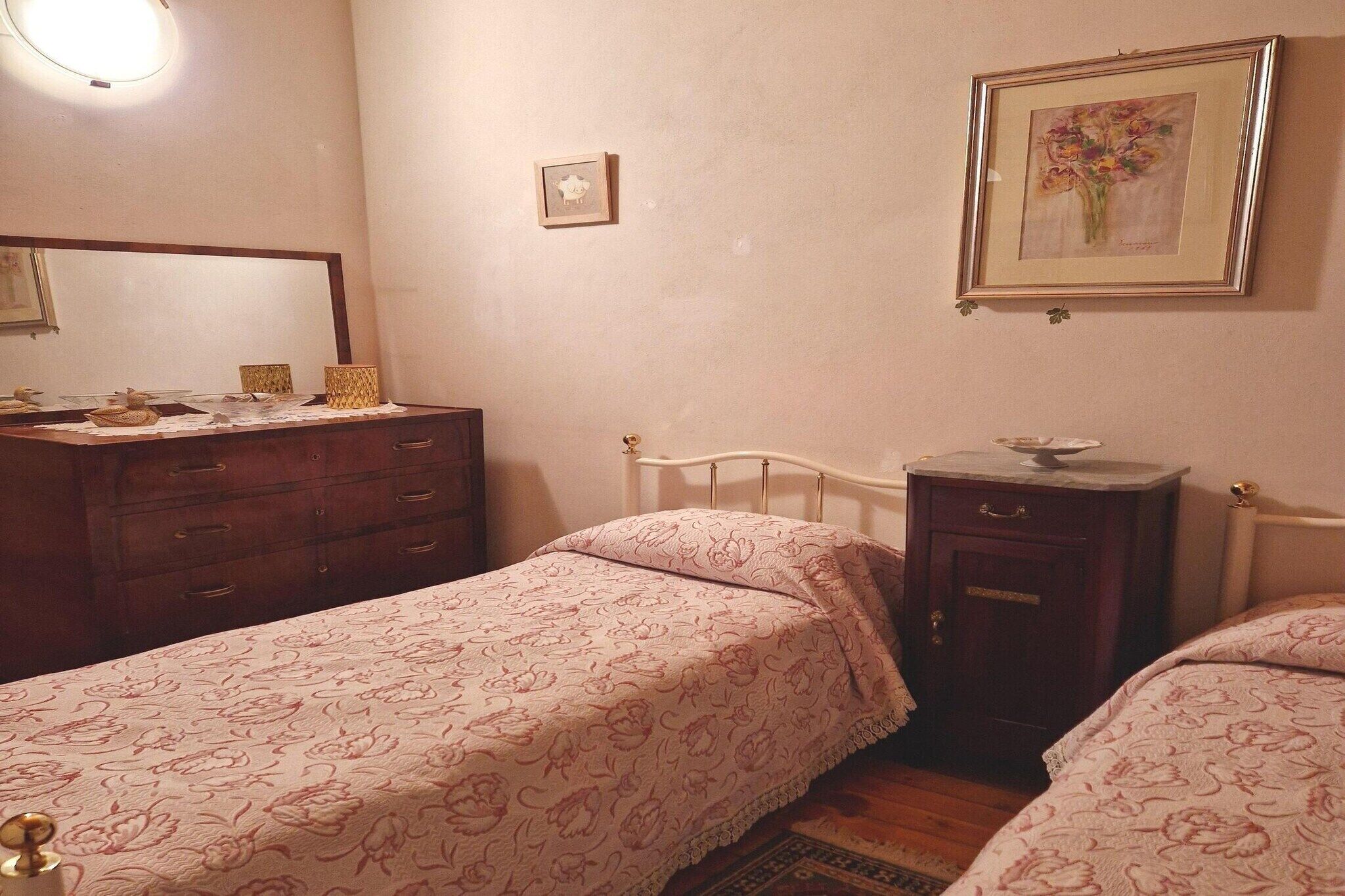A bedroom with two single beds, a dresser, a vanity, and a framed picture on the wall.