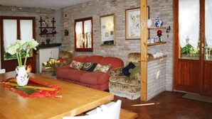 Ein gemütliches Wohnzimmer mit einer Ziegelwand, einem Holzespeisetisch, einem roten Sofa und einem gemusterten Sessel.