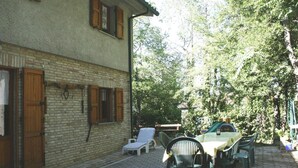 Ein Innenhof mit einem Backsteingebäude, Sitzgelegenheiten im Freien und üppigem Grün.