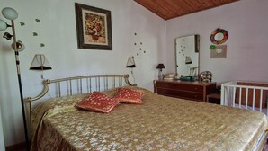Ein Schlafzimmer mit Bett, Schminktisch, Spiegel und Heizkörper.