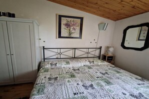 A bedroom with a bed, a wardrobe, a framed picture, a small table, and a mirror on the wall. - Farmhouse in Fano with Pool & Adriatic Views (Colli al Metauro)