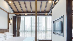 A hotel room with a large bed, a TV mounted on the wall, and a view of the city through large windows. - Floral Hotel Yuan Ju Hangzhou (Hangzhou)