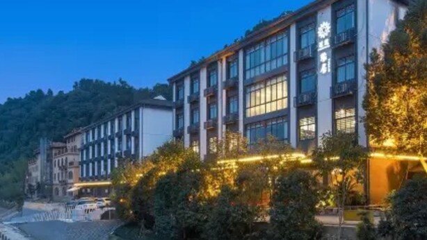 A multi-story hotel with a modern architectural design, featuring large windows and a well-lit facade. - Floral Hotel Yuan Ju Hangzhou (Hangzhou)