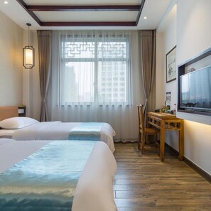 A hotel room with two beds, a wooden desk, a television, and a window with curtains. - Floral Hotel Yuan Ju Hangzhou (Hangzhou)