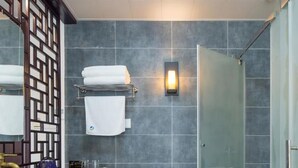 A modern bathroom with a large mirror, a wooden cabinet, a sink with a bowl, a towel rack, and a shower area. - Floral Hotel Yuan Ju Hangzhou (Hangzhou)