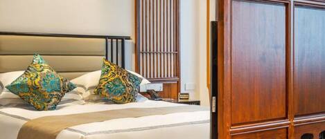 A neatly made bed with patterned pillows, a wooden headboard, and a nightstand with a lamp.
