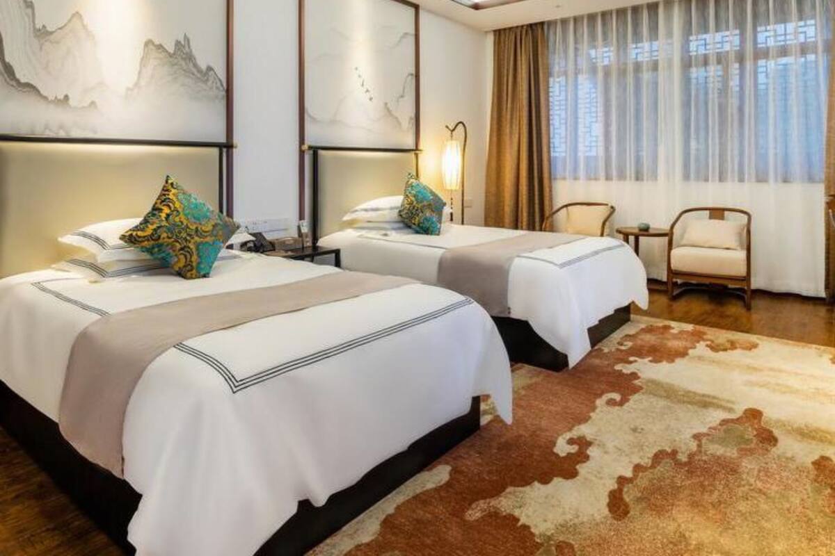 Une chambre d’hôtel avec deux lits, une grande fenêtre avec des rideaux, un plafond en bois et une œuvre d’art accrochée au mur.
