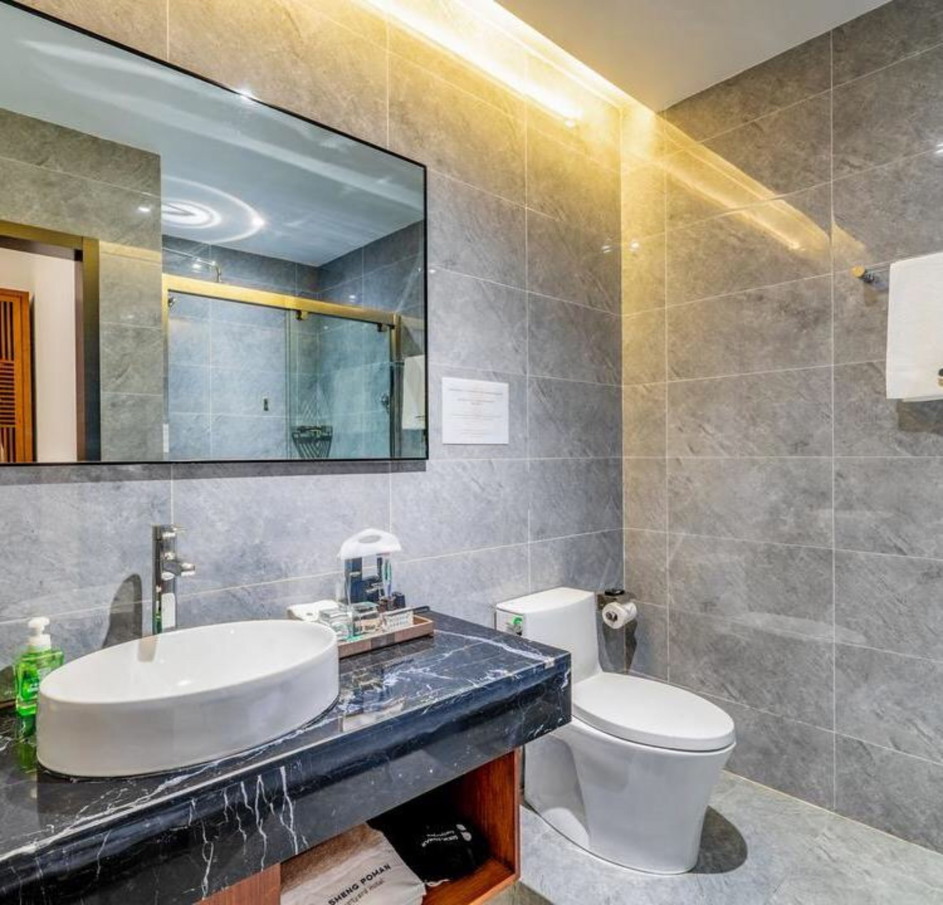 Um banheiro moderno com um espelho grande, duas pias, vaso sanitário e piso de mármore.