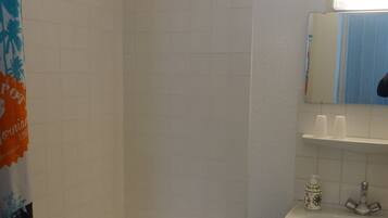 A bathroom with a bathtub, a sink, a mirror, and a trash bin.