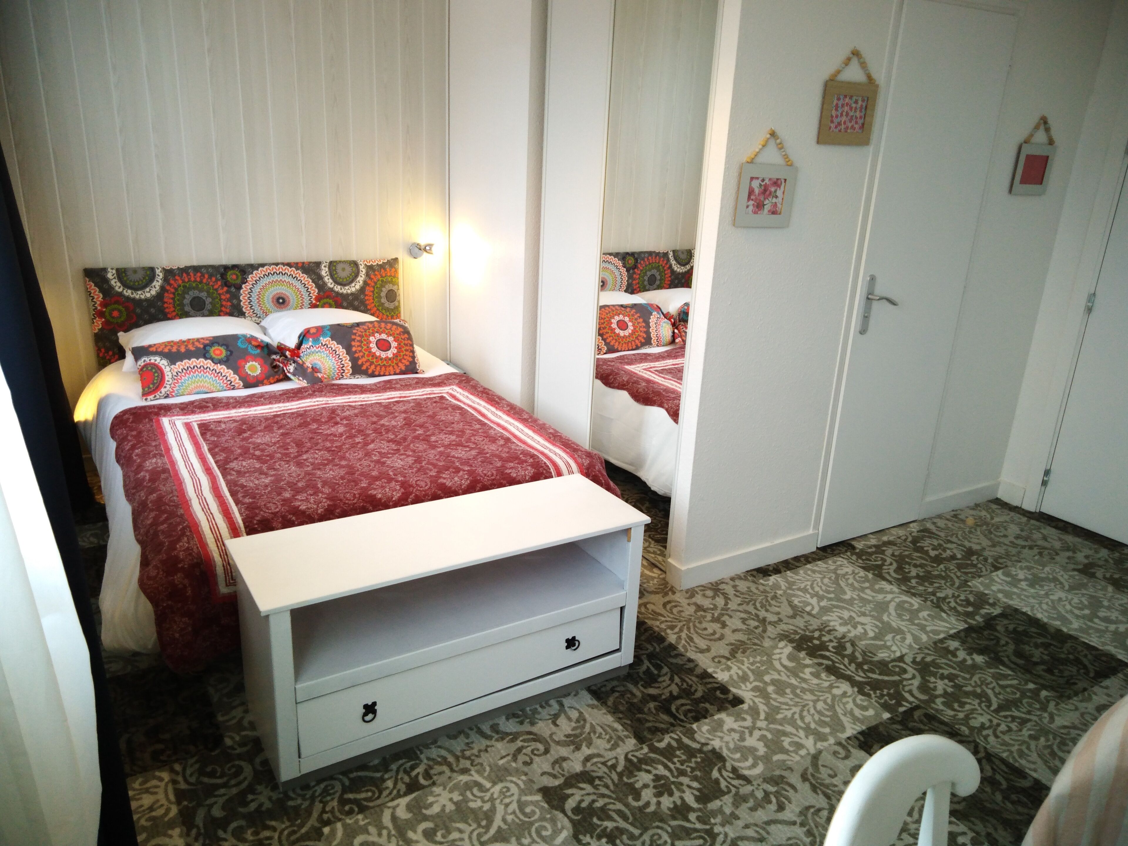 A bedroom with a bed, a wardrobe, and a small white chair.