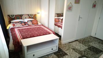 A bedroom with a bed, a wardrobe, and a small white chair.