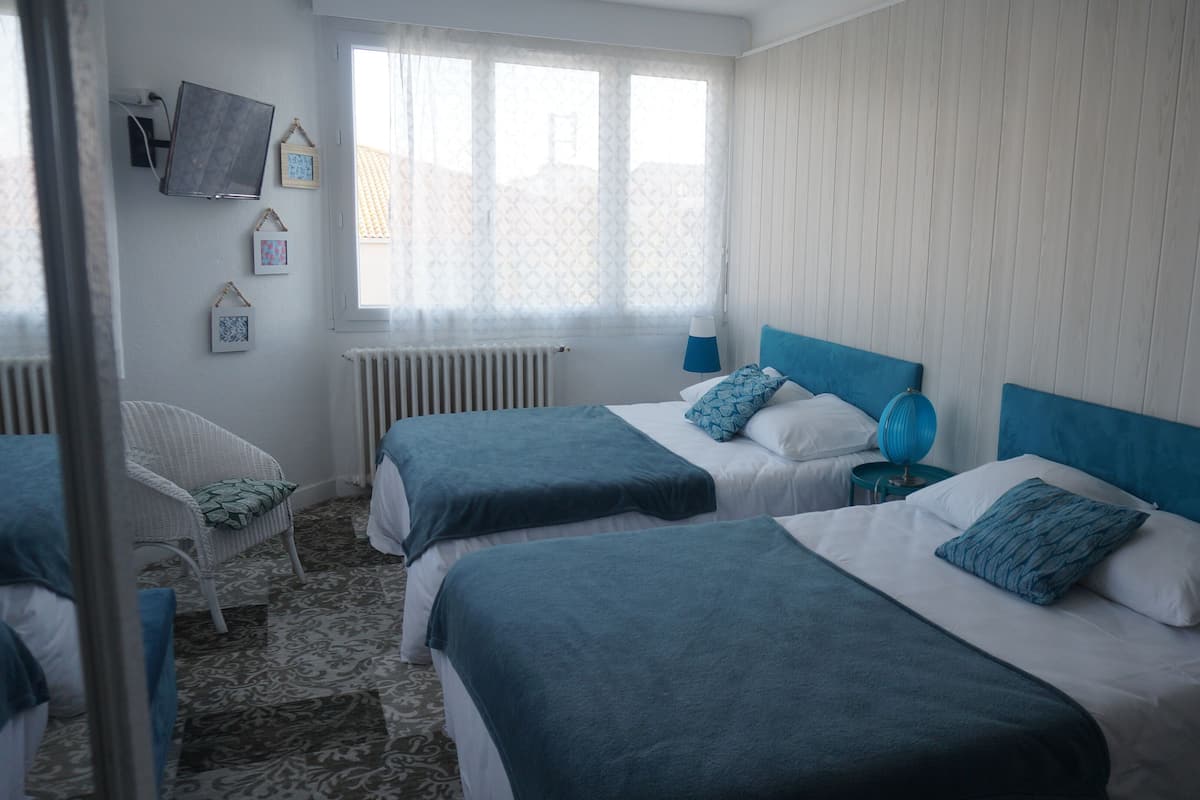Een hotelkamer met twee bedden, een stoel, een televisie en een raam met gordijnen.