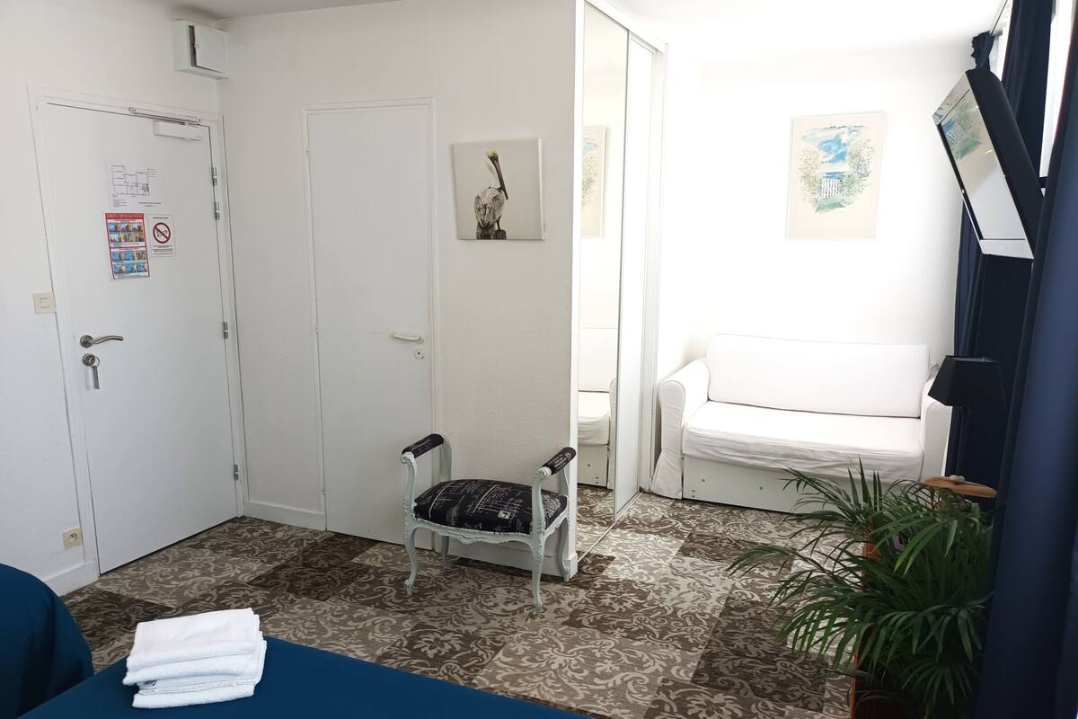 Een kamer met een bed, een stoel, een bank, een kleine tafel en een plant in een pot.