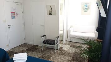 A room with a bed, a chair, a sofa, a small table, and a potted plant.